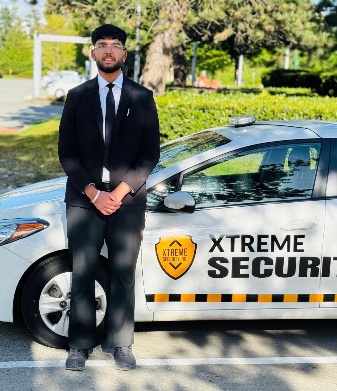 Xtreme Security officer in suit and tie with patrol car
