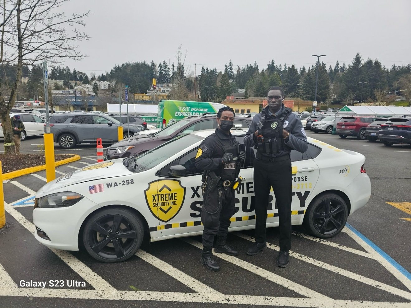 Two Xtreme Security officers with patrol car in parking lot